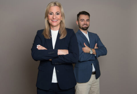 Drei Personen in Businesskleidung lächeln freundlich.