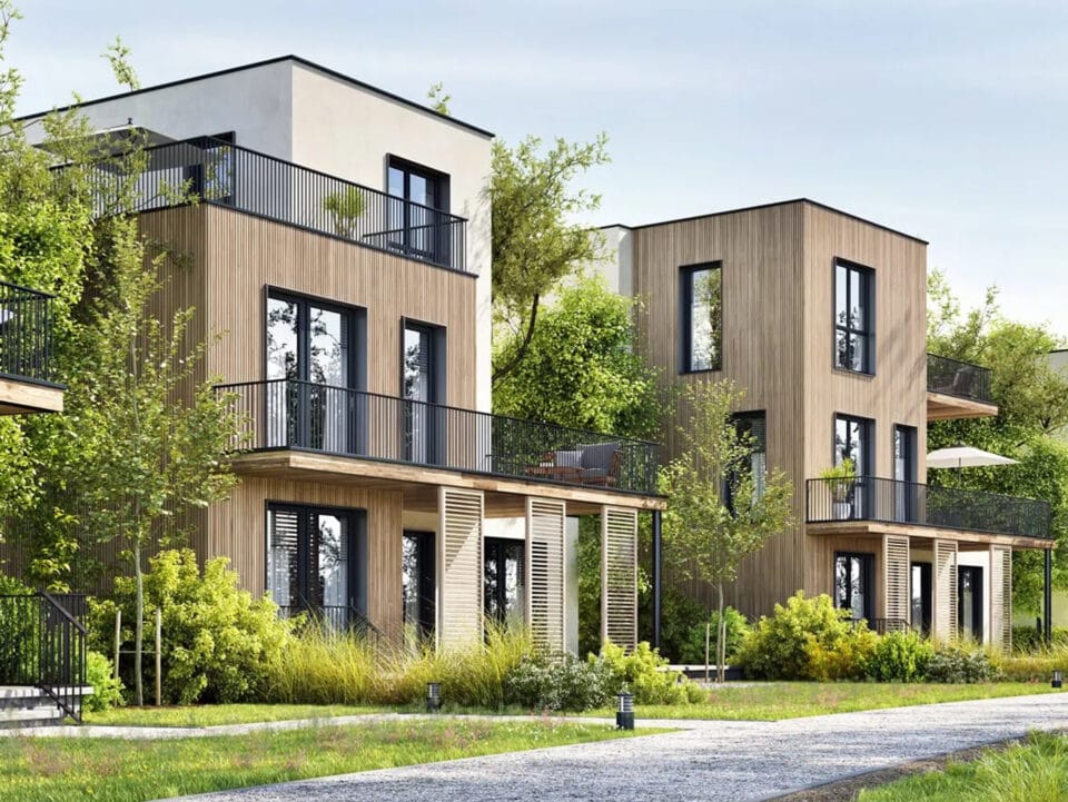 Moderne Holzhäuser mit Balkonen in grüner Umgebung.